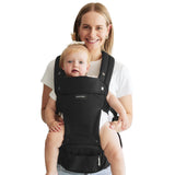 Momcozy Move2Fit Hip Seat Carrier, black, in use. Mother with baby comfortably wearing the carrier.
