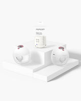 Momcozy M5 Wearable Breast Pump and milk storage bag on a pedestal, showcasing sleek design.