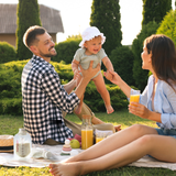 Family enjoying a picnic outdoors while using Momcozy products with baby.