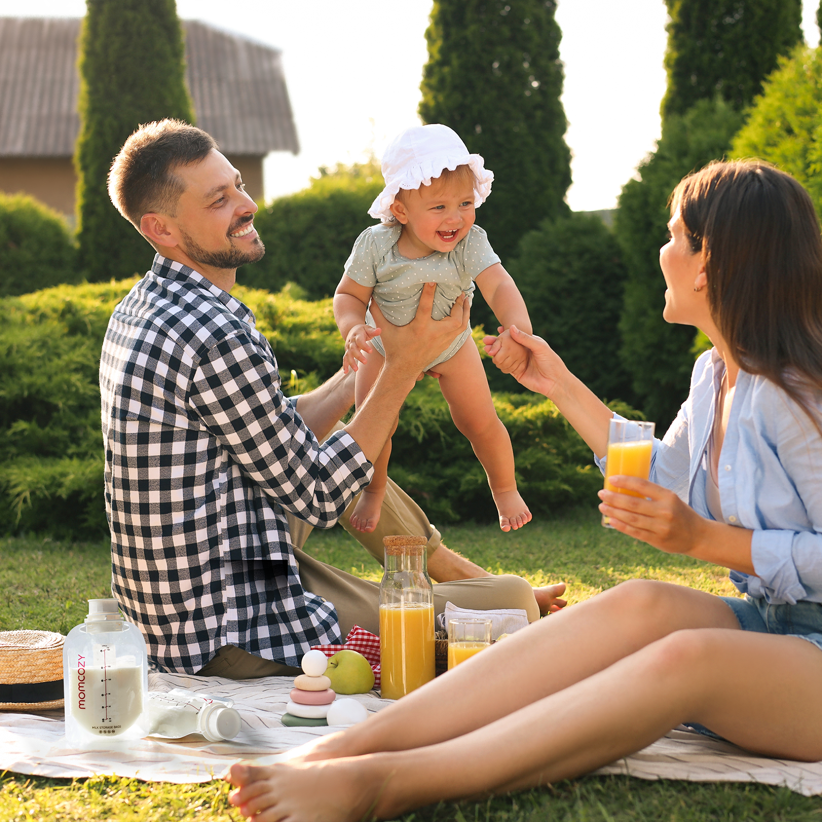 Family enjoying a picnic outdoors while using Momcozy products with baby.