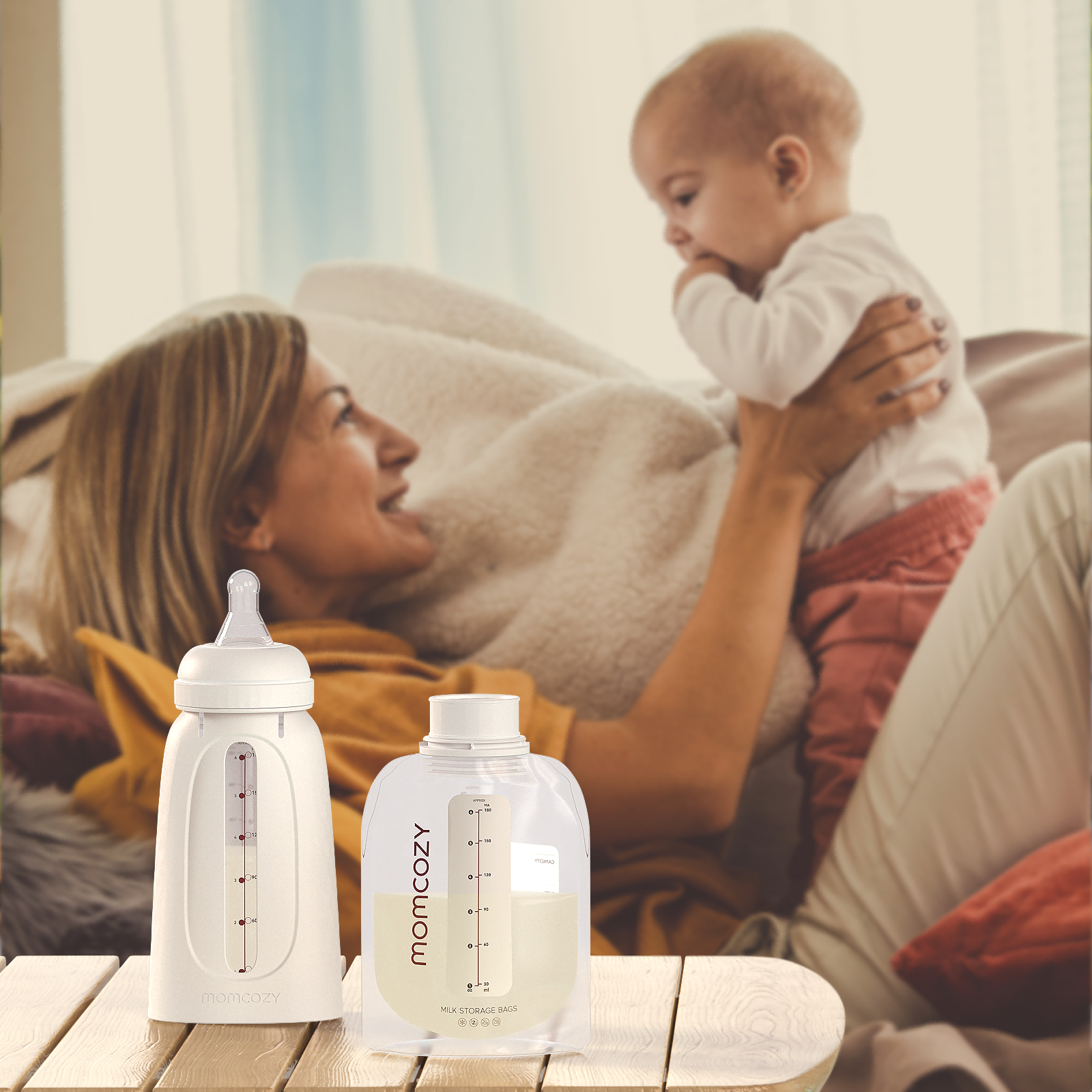 Momcozy breast milk bottle and storage container with mother feeding baby on sofa.