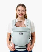 Momcozy baby carrier in light blue, supporting a sleeping baby, worn by a smiling parent, featuring the Momcozy logo.
